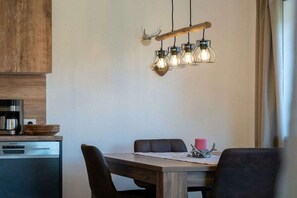 Ein Essbereich mit Holztisch, Stühlen und einer modernen Pendelleuchte.