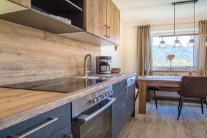 A modern kitchen with wooden cabinetry, a built-in oven, and a coffee maker. - Stubai farmhouse apartment (Telfes)