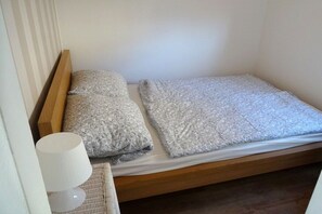 A single bed with a wooden frame, two pillows, and a white lamp on a bedside table. - Baltic Sea Idyll Bungalow 4 Seal (Ostseebad Nienhagen)