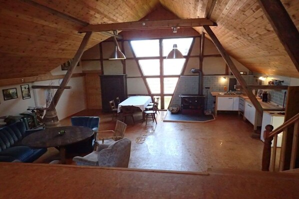 An attic room with a dining area, seating, and a wood-burning stove.