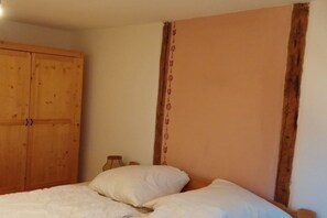 A bedroom with a wooden wardrobe, a bed with white bedding, and a wall with a vertical decorative pattern. - Cabin in Drognitz with swimming pool (Drognitz)