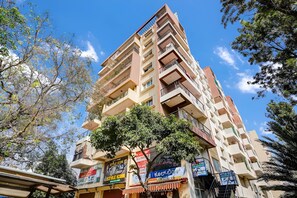 A multi-story building with balconies, a tree in front, and various signs including 'Style Icon' and 'Spare'. - Hotel K L Rooms (Bengaluru)
