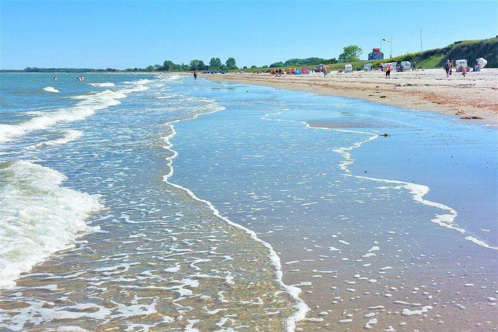 A beach with waves, people, and beachgoers.