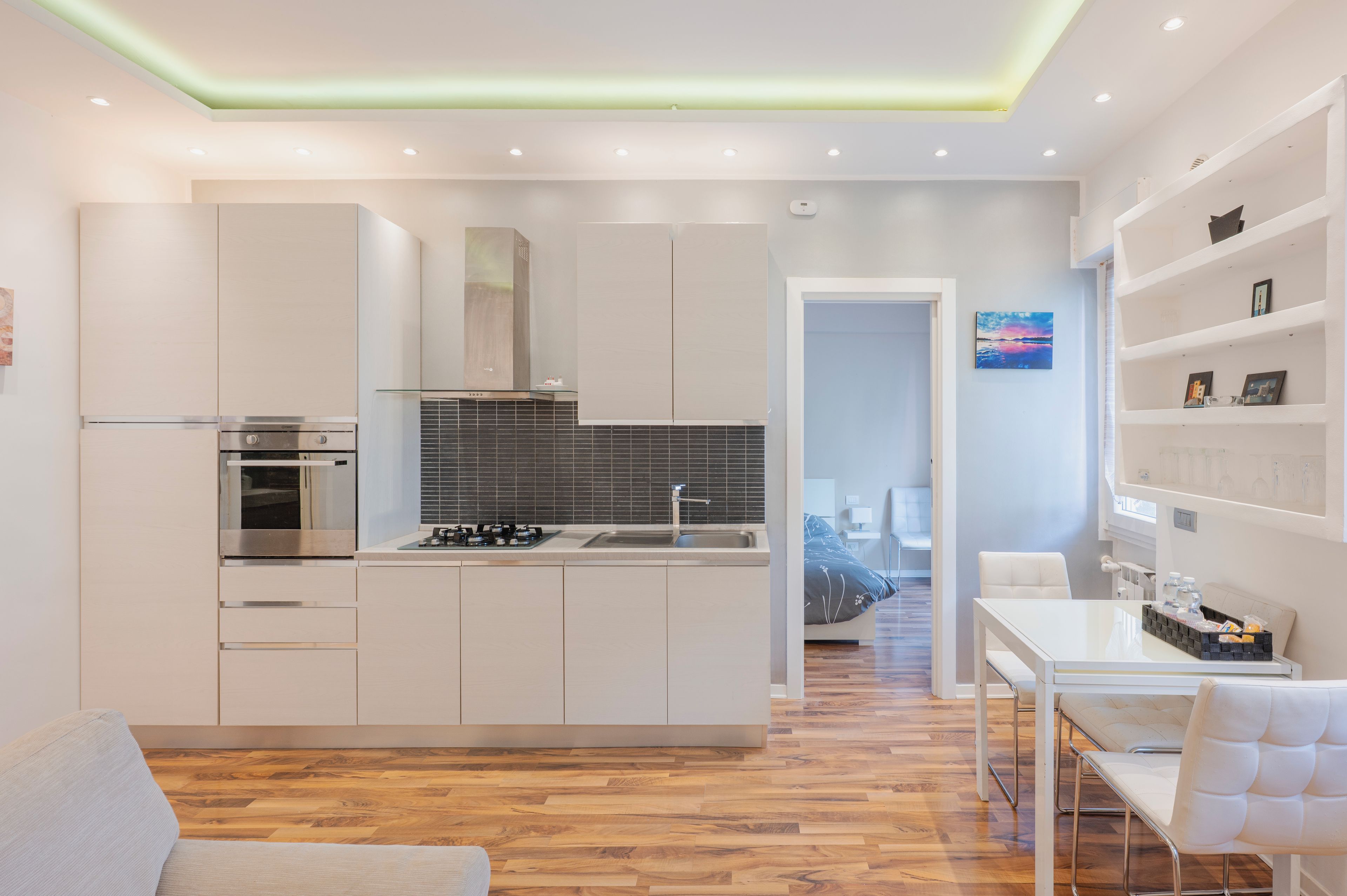 A modern kitchen with white cabinetry, a built-in oven, and a gas stove.