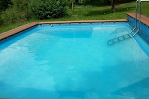 A rectangular swimming pool with a wooden deck edge and a metal ladder on one side. - Cozy holiday home with pool (Marienberg)