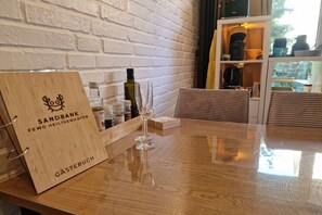 A wooden table with a glass wine glass, a corkscrew, and a corkboard with a logo. - Holiday apartment with 2 bedrooms (Heiligenhafen)
