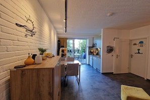 A modern kitchen with a wooden countertop, a dining area with chairs, and a view to the outside. - Holiday apartment with 2 bedrooms (Heiligenhafen)