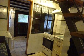 Eine kleine Küche mit Herd, Backofen und einem Fenster mit Spitzendecke.