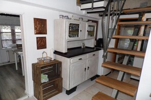 Eine Küche mit einem weißen Schrank, einem Holzboden und einer Treppe.
