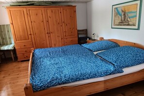 Ein Schlafzimmer mit einem hölzernen Bett, einem Holzschrank, einem Stuhl und einem Gemälde an der Wand.