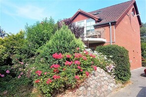 A red brick house with a stone wall and a balcony. - Holiday apartment with 3 bedrooms (Schönhagen)