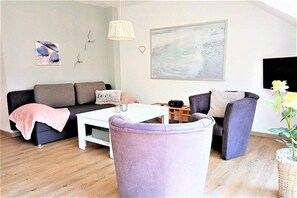 A living room with a sofa, armchairs, a coffee table, and a painting on the wall. - Holiday apartment with 3 bedrooms (Schönhagen)
