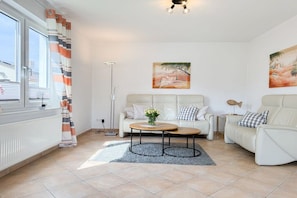 A modern living room with a sofa set, a coffee table, and artwork on the walls. - Holiday home Melanie (Scharbeutz)