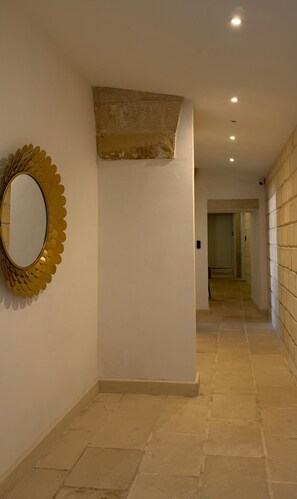 A hallway with a decorative mirror and recessed lighting.