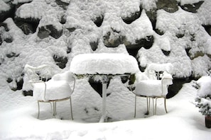 Un espace extérieur aménagé avec des sièges, recouvert de neige, comprenant une table et deux chaises.
