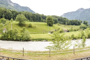 Un paisaje rural con un río, campos verdes y algunas casas.