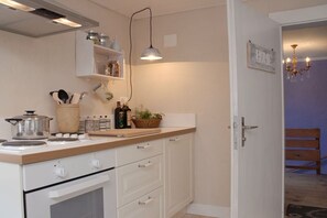 A kitchen with white cabinets, a wooden countertop, a stove, and a hanging light fixture. - Holiday apartment with 2 bedrooms (Wilderswil)