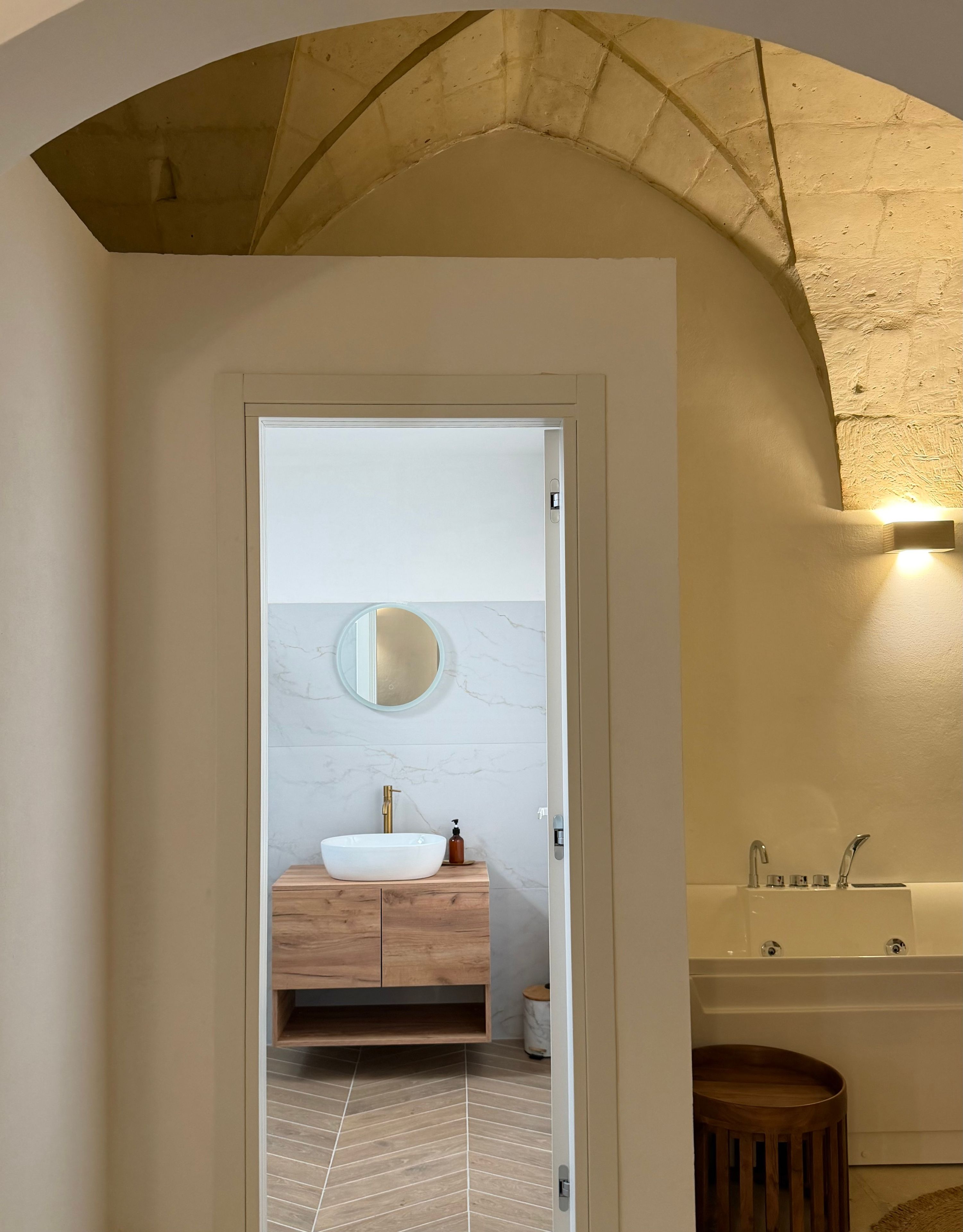 Une salle de bain moderne avec une baignoire sur pieds, un meuble-lavabo doté d’un grand miroir et un sol à motifs en chevrons.