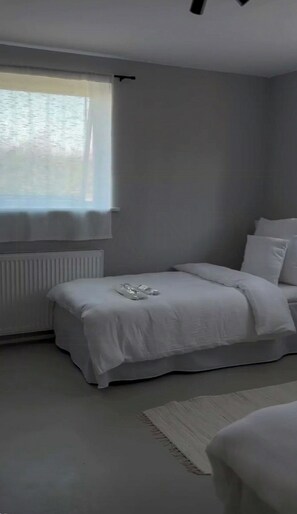 A minimalist bedroom with a bed, a radiator, and a window. - Family home with views over Ebeltoft Bay (Ebeltoft)