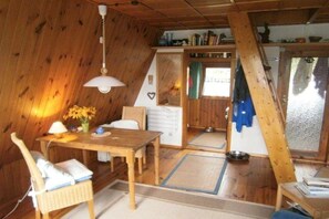 A wooden interior with a dining table, chairs, a hanging lamp, and a window with a view. - Holiday home with 2 bedrooms (Alt Globsow)