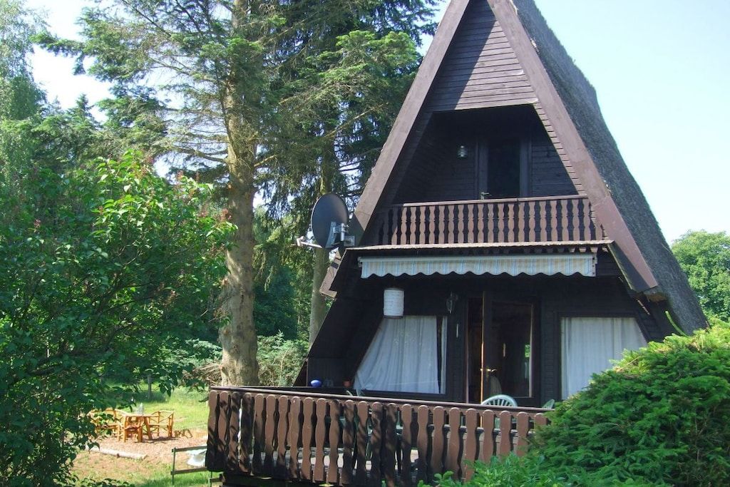 A wooden cabin with a balcony, surrounded by trees.