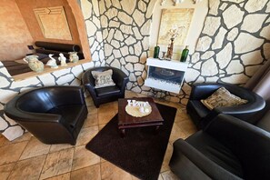 A living room with stone walls, a fireplace, and leather armchairs. - Pug holiday pure holiday with south-facing balcony 009 (Burgtiefe-Südstrand)