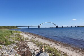 Une rivière avec un pont, des galets et une végétation clairsemée.