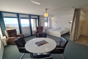 Ein Zimmer mit einem Bett, einem Esstisch mit Stühlen, einem Fenster mit Aussicht und einem Sessel.