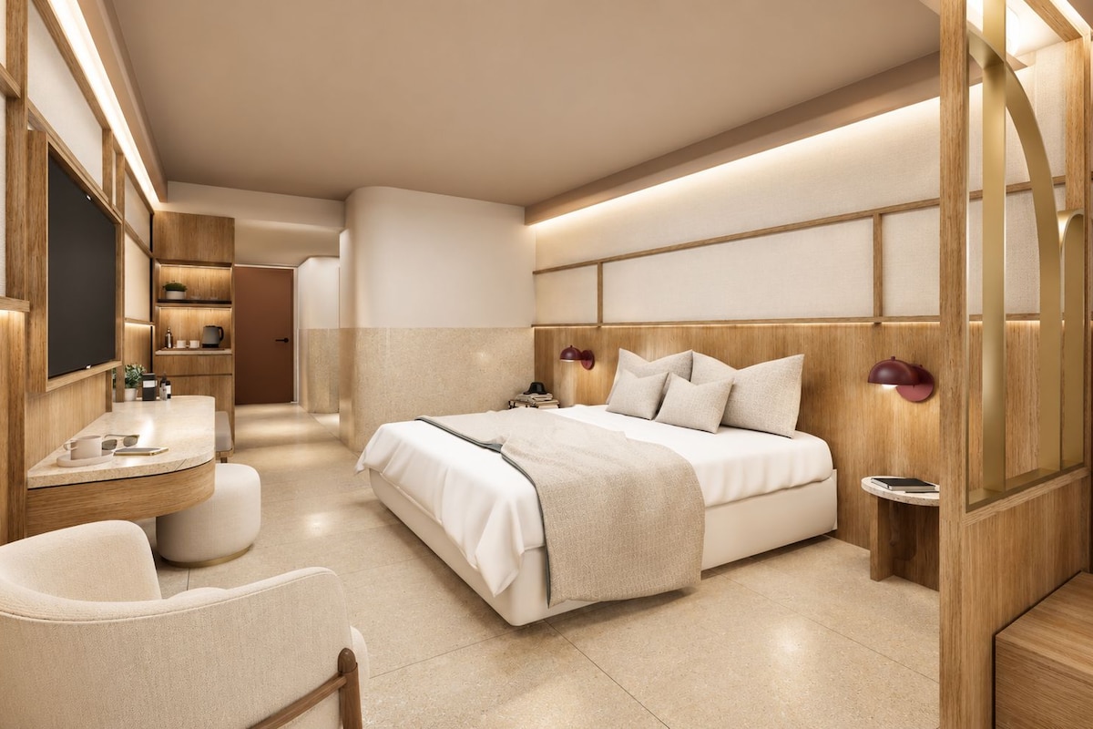 A modern bedroom with a bed, bedside table, lamp, and a view of the hallway.