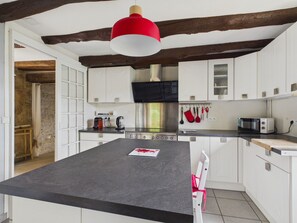 A modern kitchen with white cabinets, a central island, and a red pendant light. - House for 8 with heated pool (La Bachellerie)