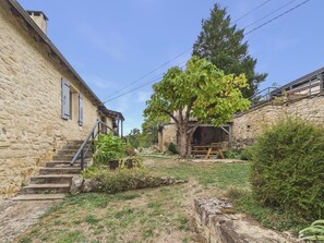 A stone building with a staircase leading to a wooden deck. - House for 8 with heated pool (La Bachellerie)