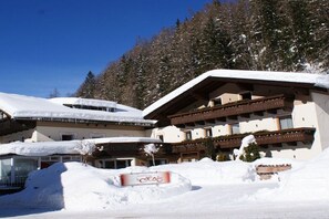 Ett hotell med flera balkonger, snötäckta tak och en skylt som visar att det är ett skidområde.