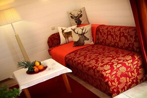 A cozy room with a red sofa, patterned cushions, a small table with fruit, and a lamp. - Apartment with 1 bedroom (Heiligenblut am Großglockner)