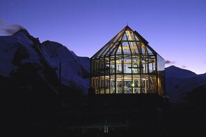 A glass-roofed structure with a triangular base, surrounded by snow-covered mountains. - Apartment with 1 bedroom (Heiligenblut am Großglockner)