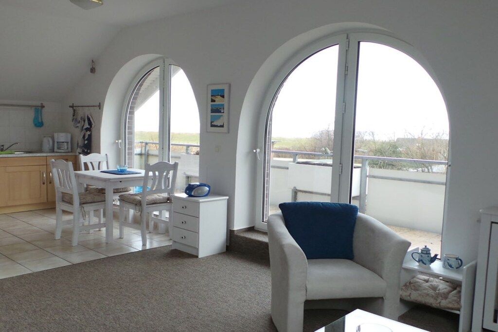 Un salon moderne avec un coin repas, des meubles blancs et de grandes fenêtres en arc de cercle.