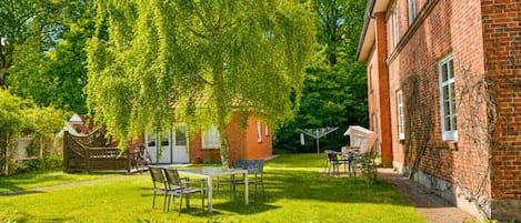 A brick building with a garden patio, a table, and chairs.