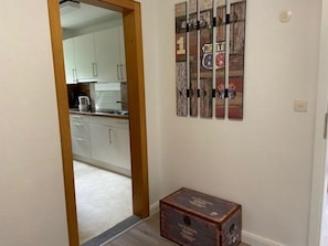 A hallway with a wooden door leading to a kitchen area. There is a vintage-style box on the floor. - Holiday Apartment With 1 Bedroom (Wyk auf Foehr)