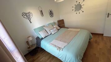 A bedroom with a bed, a bedside table, a lamp, and wall decorations.