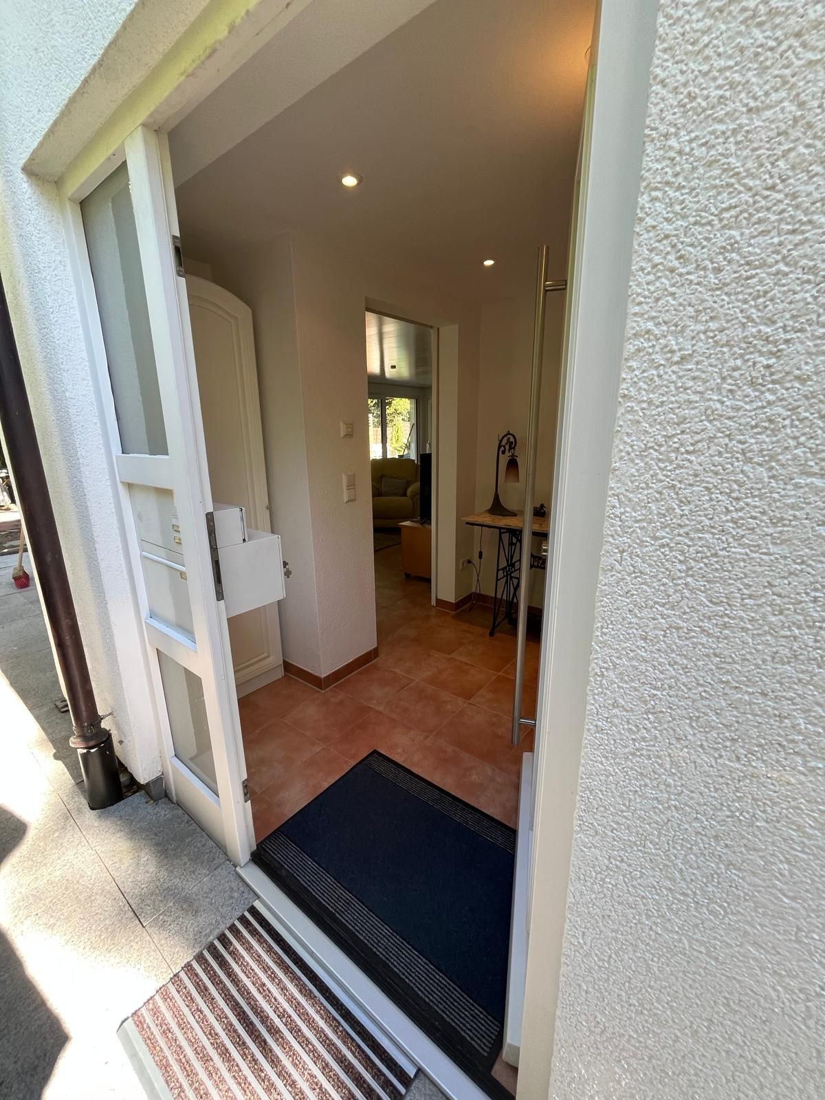 An open door leading to a living area with a sofa, a table, and a lamp.