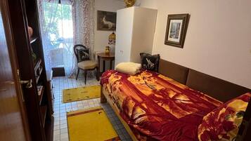 A bedroom with a bed, a wardrobe, a desk, and a chair.