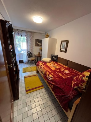 A bedroom with a bed, a wardrobe, a desk, and a chair.