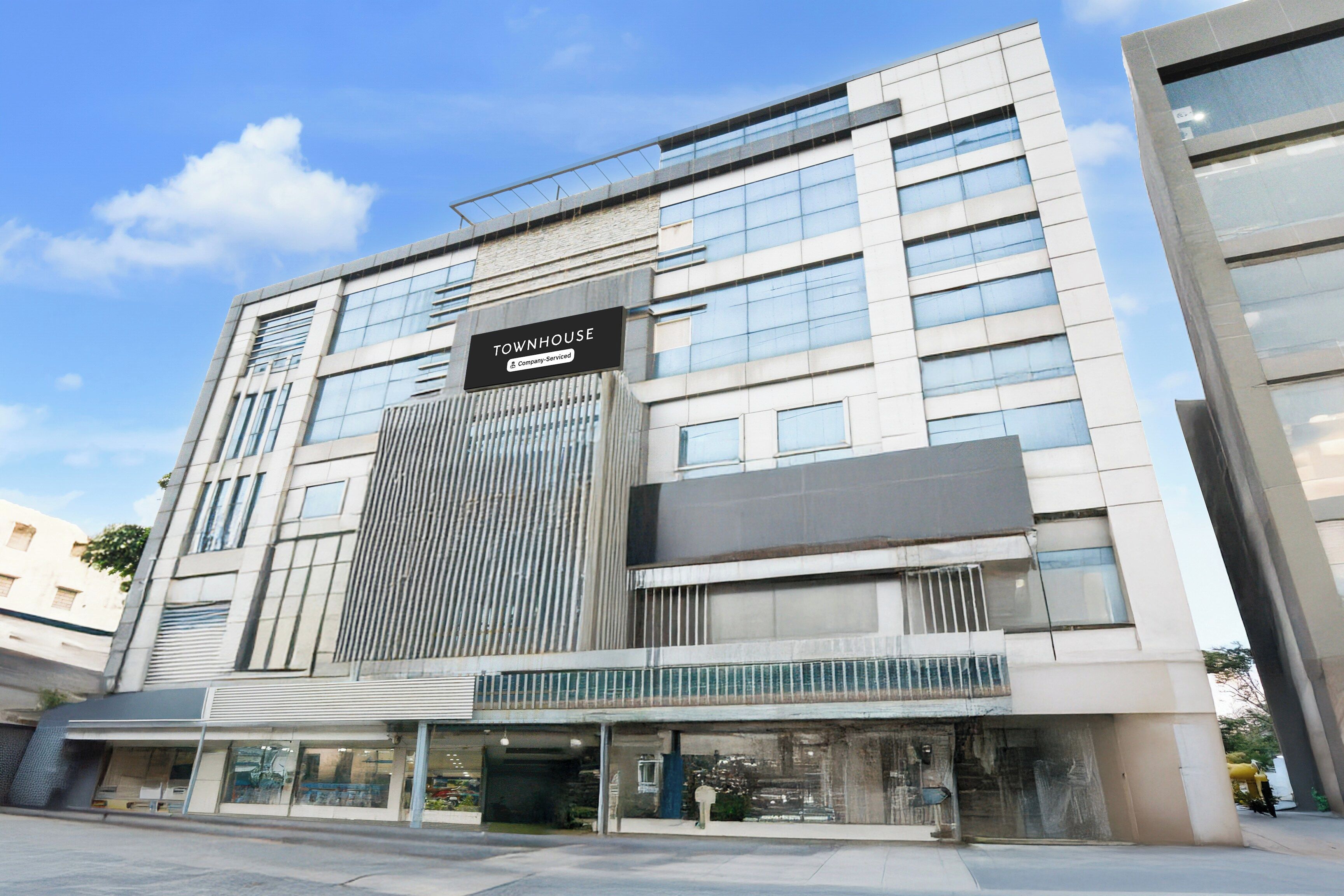 Un edificio moderno con un letrero que dice 'TOWNHOUSE' y un rótulo de servicio de empresa.