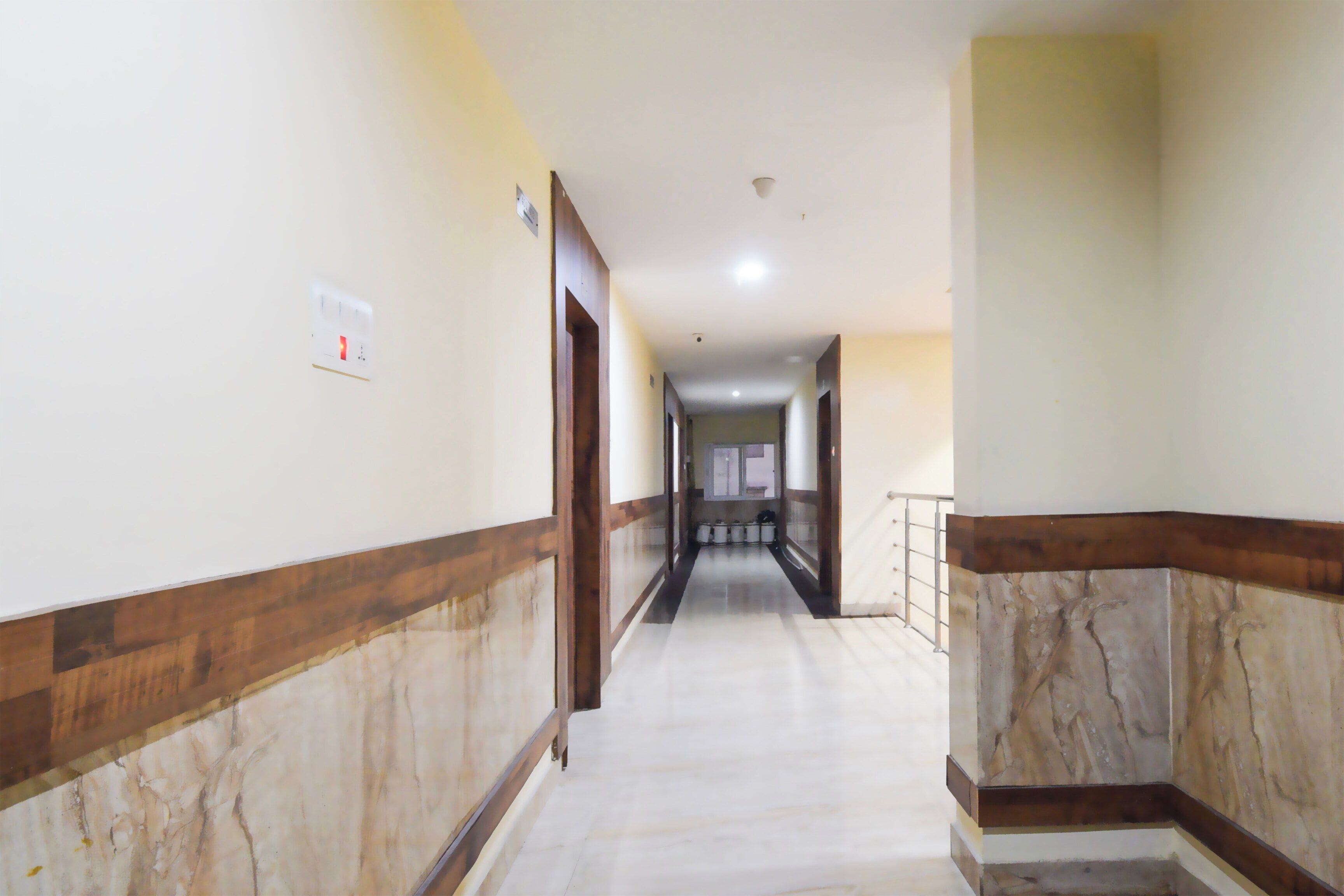 A corridor with marble flooring and wooden trim, leading to a door at the end.