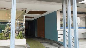 A corridor with a glass wall on one side, a staircase with a green carpet, and a blue wall on the other.