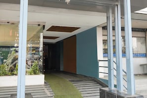 A corridor with a glass wall on one side, a staircase with a green carpet, and a blue wall on the other. - Townhouse Vanasthalipuram (Hyderabad)