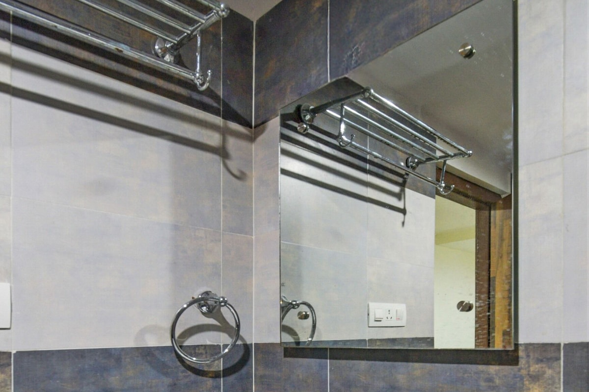 A bathroom with a white sink, a towel rack, a mirror, and tiled walls.