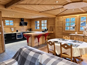 A wooden interior with a kitchen, dining area, and a sofa. - New Listing (Les Allues)