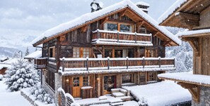 A multi-story wooden chalet with balconies, surrounded by snow-covered trees. - New Listing (Les Allues)