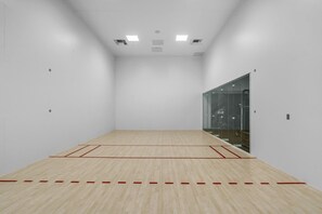 A squash court with a wooden floor and glass walls. - Miami Escape 1807 for 4 (Miami)