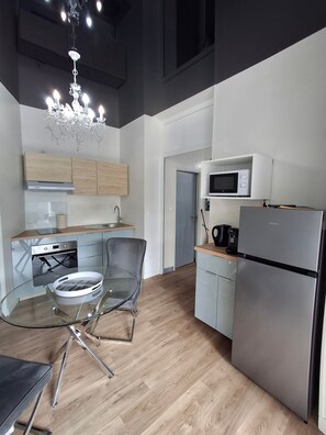 A modern kitchen with a glass dining table, stainless steel appliances, and a chandelier. - Apartment 'La Discrète Romantique' with Hot Tub, Wi-Fi and Air Conditioning (Charavines)